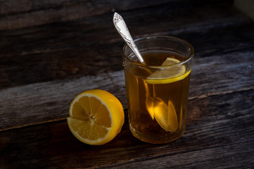 Tea with lemon in a glass on a wooden background.