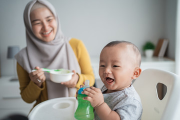 Little asian child eating rice soup from mother feeding