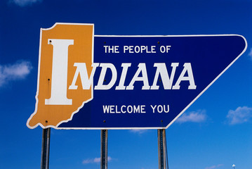 This is a road sign that says the people of Indiana welcome you. It is a welcome to Indiana road sign against a blue sky. - obrazy, fototapety, plakaty