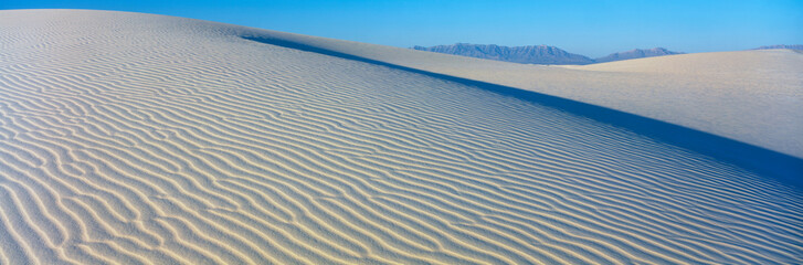 These are sand dunes in the morning. There are lines in the sand that form a pattern from the wind.