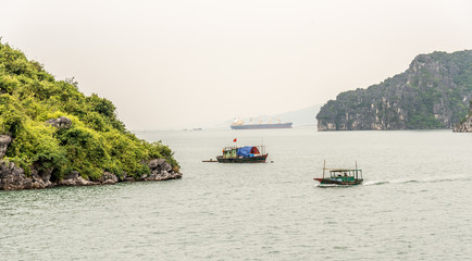 Fototapeta na wymiar Traditional Vietnamese Fishing Boat Surrounded by Karst Mountains in Bai Tu Long Bay in Halong Bay Vietnam on a Cloudy Day