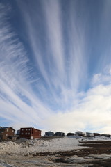 View of an high arctic community and neighbourhood with blue skies and some snow on the ground, located in Cambridge Bay, Nunavut Canada