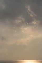 Seascape in pastel colors. Ships and the sea, lit by the pale sun, shining through the clouds.