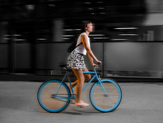 Fototapeta na wymiar young hipster girl driving blue bicycle, motion blur, city ride 