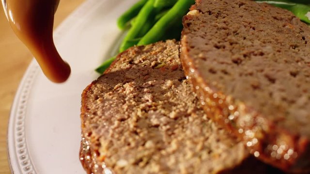 Gravy poring over meatloaf in close up slow motion