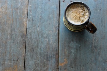Coffee with foam in a ceramic mug, rustic blue table, copy space, horizontal