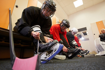 Low angle view at female hockey team putting on gear in locker room while preparing for match or...