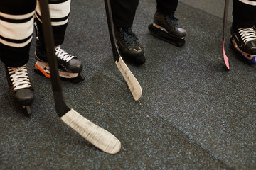 Background image of hockey team players ready for match in locker room, closeup shot of skating shoes and hockey clubs, copy space