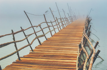 Vietnamese bamboo bridge across the misty river.