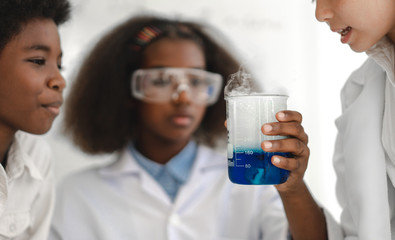 Group of teenage students learning and doing a chemical experiment and holding test tube in hands in the experiment laboratory class on table at school.Education concept