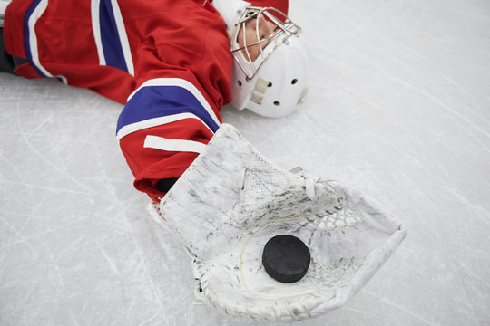 Close Up Of Female Hockey Player Lying On Ice And Holding Pluck Exhausted After Practice, Copy Space