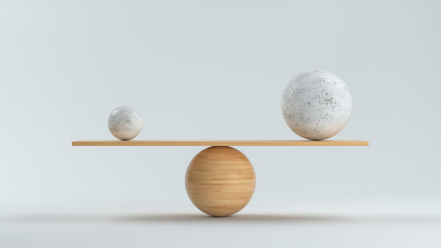 wooden scale balancing a small and a big ball in front white background