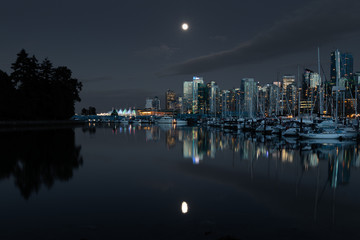 Fototapeta na wymiar Downtown vancouver canada on a clear night with a full moon reflection