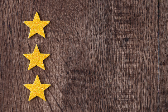 Gold glitter stars in a border on dark wood as a background