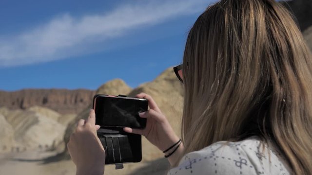 Adventurous young female girl taking photos on phone smart device Death Valley