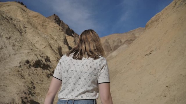 Travel and adventure young woman hiking dry desert canyon exploring Death Valley