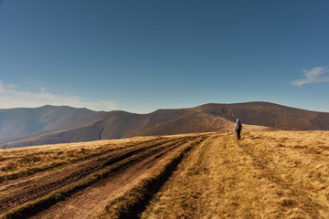 Adorable autumn landscapes in Carpathian mountains with beautiful tourist girl traveling with red tent
