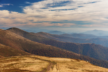Adorable autumn landscapes in Carpathian mountains with beautiful tourist girl traveling with red tent