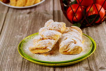 Powdered apple strudel on green plate with fresh apples.