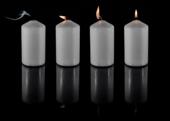 vier weiße Kerzen vor schwarzem Hintergrund 
