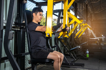 Sport Man doing fitness training on a butterfly machine with weights in a gym
