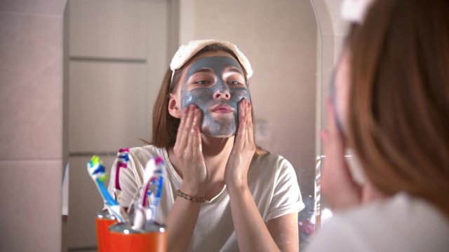 A young woman washes off the mask from the face
