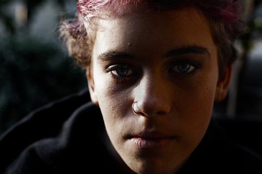 Portrait of  depressed teenage girl with short hair in dark, moody light