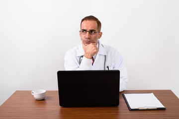 Mature Persian man doctor working behind desk