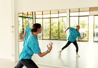 One European young woman dancing modern choreography in a fitness room in front of a mirror