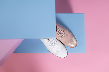 women's shoes of different colors, but of the same model, stand on a pink, blue stand from the studio. Promotional photo