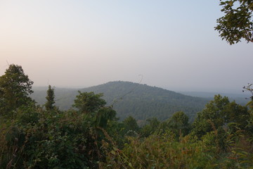 Landscapes of a small hill and green natural forest viewing from another hill