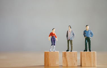 Gender equality concept, miniature female figurine stand same level as male figurines - obrazy, fototapety, plakaty