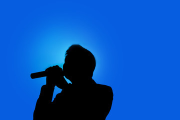 silhouette of man shadow hoding microphone in two hands.