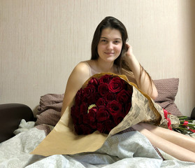 pretty girl sitting in bed with a huge bouquet of roses.
