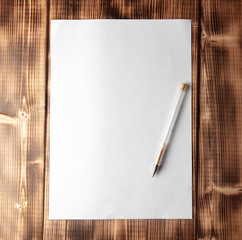 White paper with pen on a wooden table