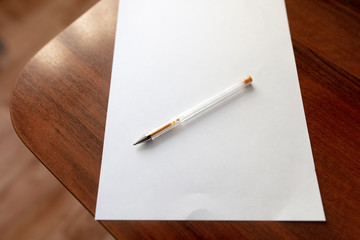 White paper with pen on a wooden table