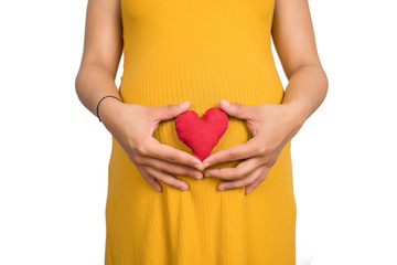 Pregnant woman holding heart sign on belly.