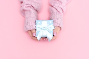 White gift box with red bow in the children's hands on pink background