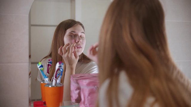 A young woman applying shadows on the eyes