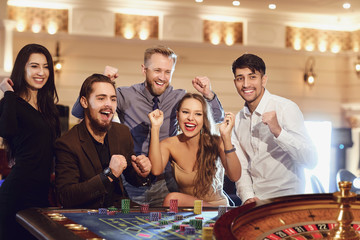 Cheerful group of friends enjoys winning poker roulette in a casino.