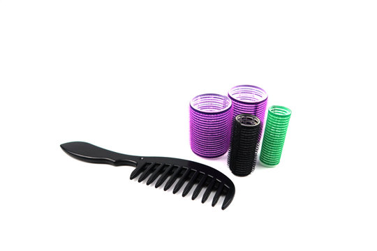 Black comb and hair curlers which are big and small size, color purple, black and green isolated on white background.