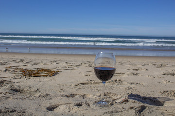 Fototapeta na wymiar glass of red wine on the sand on the beach overlooking the sea in a romantic atmosphere