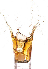 big splash from falling ice in a glass of whiskey on a white background