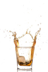 big splash from falling ice in a glass of whiskey on a white background