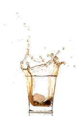 big splash from falling ice in a glass of whiskey on a white background