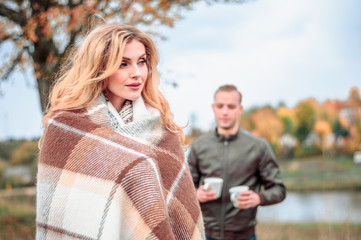 a guy treats a cup of hot tea to his girlfriend who froze in cold autumn weather and wrapped herself in a plaid, a love story and the concept of caring for a loved one