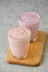 Two glasses of fruit yogurt on a wooden board