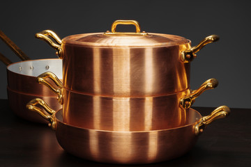 Shiny vintage copper cookware over dark background