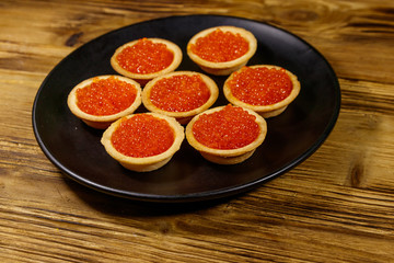 Fototapeta na wymiar Tartlets with red caviar on a wooden table