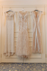 Elegant Fashion Wedding Dresses Hanging on Door. Traditional Long Fabric Silk Bridal Clothing for Ceremony Suspension on Wardrobe in Room with Beautiful Interior. Female Bright Gowns Vertical Photo